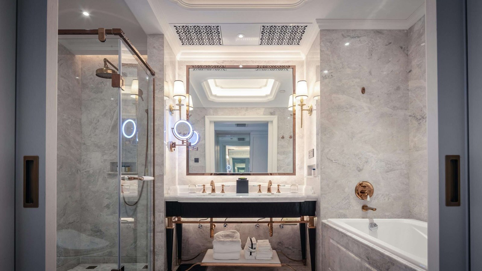 Elegant bathroom featuring a marble sink, bathtub, and mirror with ambient lighting.