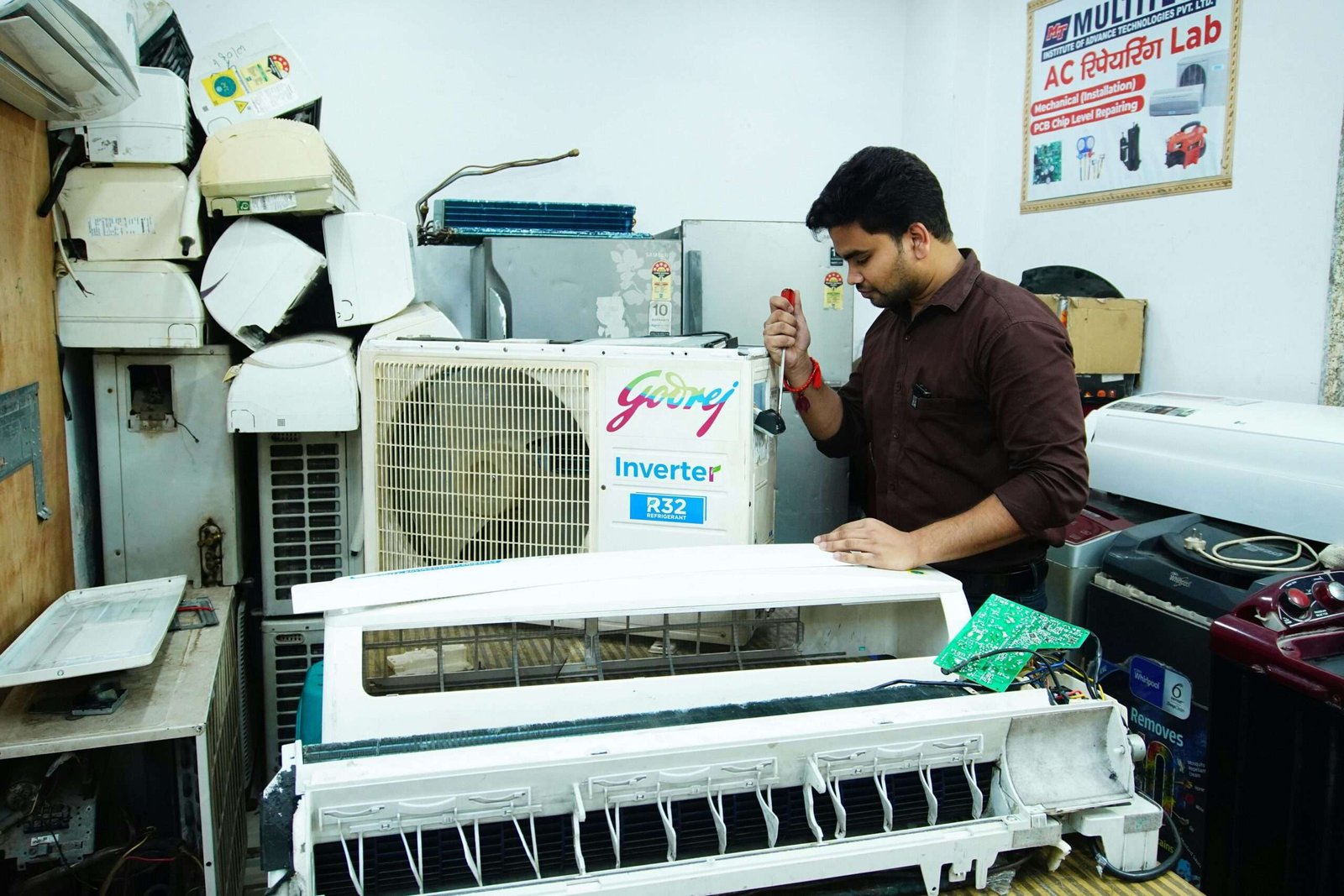 Technician repairing an air conditioner unit in New Delhi workshop.